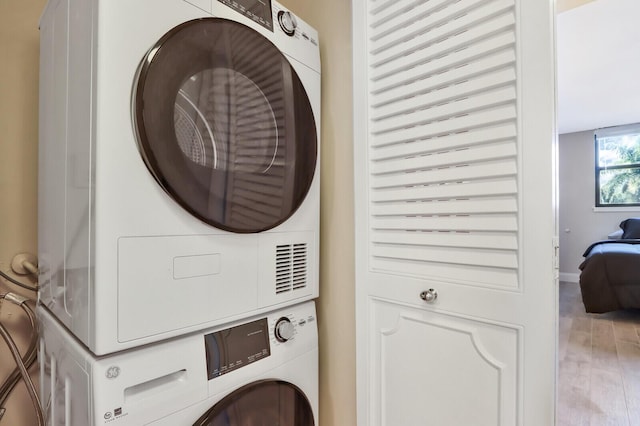 washroom featuring light hardwood / wood-style flooring and stacked washer / dryer