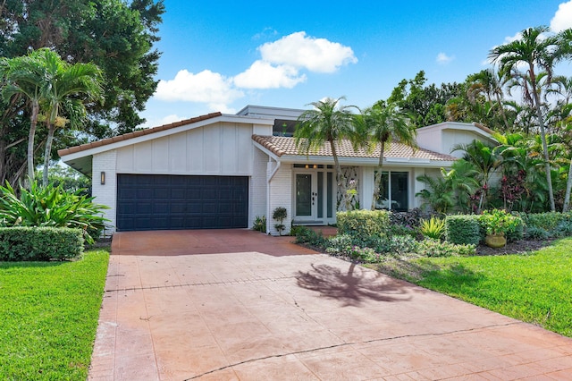 view of front facade with a garage, a front yard, and french doors