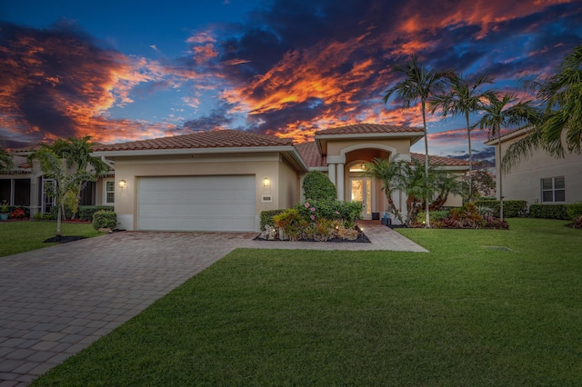 mediterranean / spanish-style home with a garage and a lawn