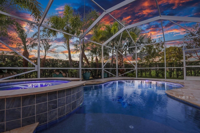 pool at dusk with glass enclosure and an in ground hot tub