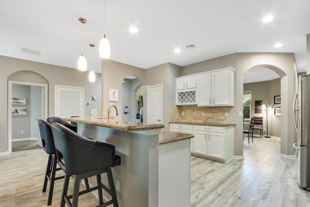 kitchen featuring sink, white cabinetry, light stone counters, hanging light fixtures, and dishwasher