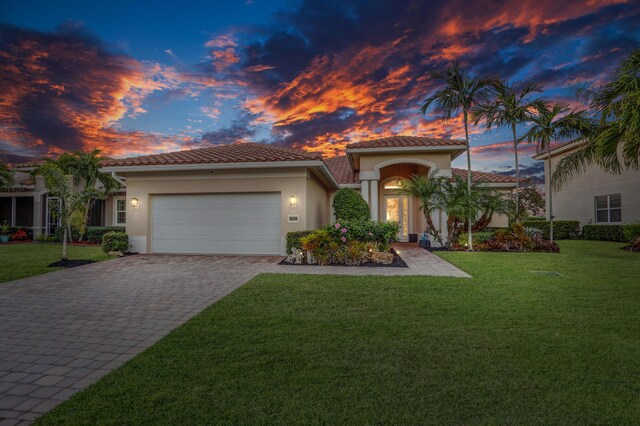 mediterranean / spanish house with a lawn and a garage