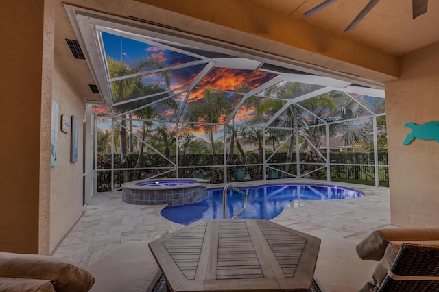 pool at dusk featuring an in ground hot tub, a lanai, and a patio area