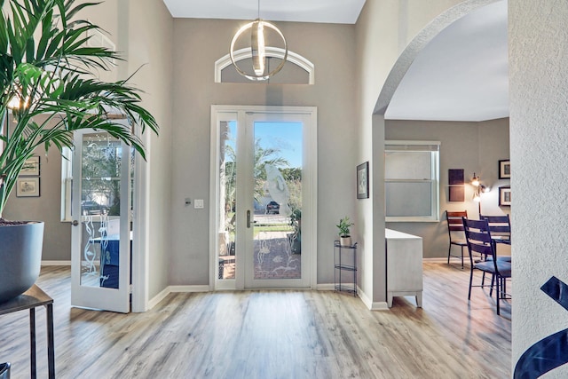 foyer entrance featuring a towering ceiling and light wood-type flooring