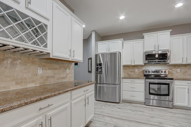 kitchen featuring stone countertops, tasteful backsplash, white cabinets, and appliances with stainless steel finishes