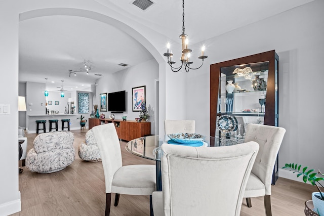 dining space featuring ceiling fan with notable chandelier and light wood-type flooring