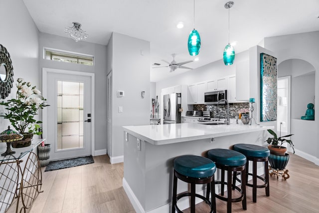 kitchen featuring ceiling fan, hanging light fixtures, stainless steel appliances, decorative backsplash, and white cabinets