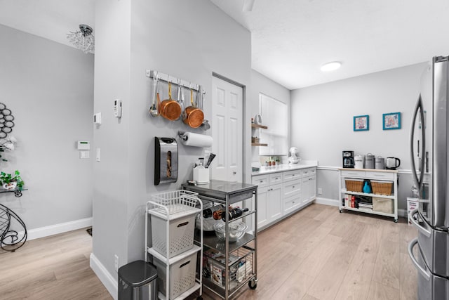 kitchen with white cabinets, stainless steel fridge, and light wood-type flooring