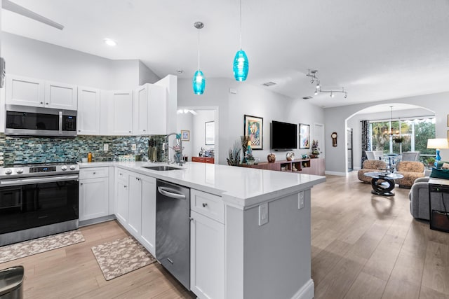 kitchen with sink, white cabinets, hanging light fixtures, and appliances with stainless steel finishes