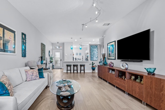 living room with a textured ceiling, light hardwood / wood-style floors, and ceiling fan