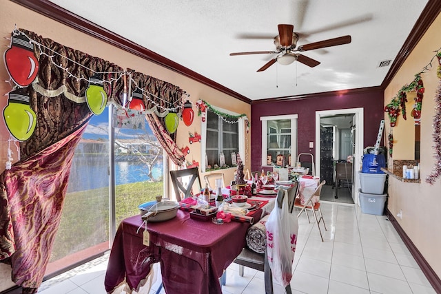 dining room featuring ceiling fan, light tile patterned floors, a textured ceiling, a water view, and ornamental molding