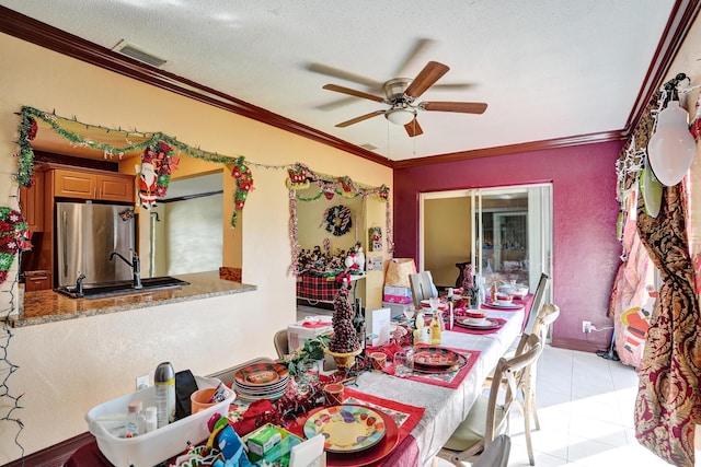 tiled dining space with a textured ceiling, ceiling fan, crown molding, and sink