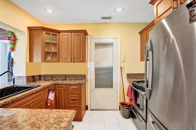 kitchen with sink, light tile patterned floors, dark stone counters, and appliances with stainless steel finishes