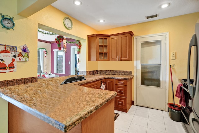 kitchen featuring light tile patterned flooring, kitchen peninsula, and fridge