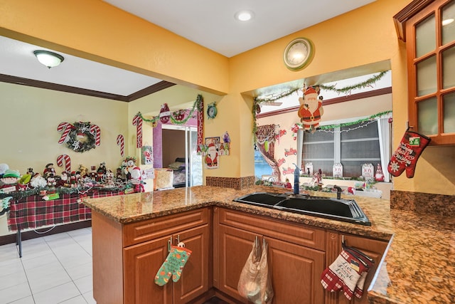 kitchen with stone counters, crown molding, sink, light tile patterned flooring, and kitchen peninsula