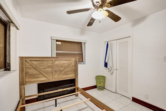 unfurnished bedroom with light tile patterned floors, a textured ceiling, a closet, and ceiling fan