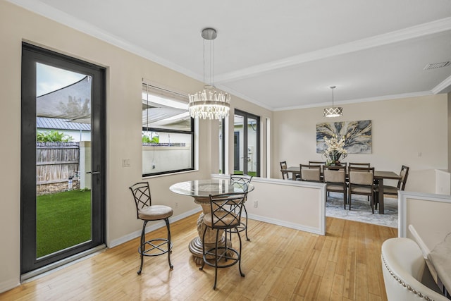 dining area featuring light wood-type flooring, crown molding, and a chandelier