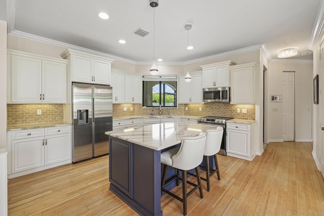 kitchen featuring appliances with stainless steel finishes, a kitchen island, sink, decorative light fixtures, and white cabinetry