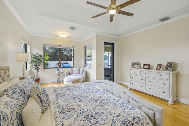 bedroom featuring ceiling fan, light hardwood / wood-style floors, ornamental molding, and a tray ceiling