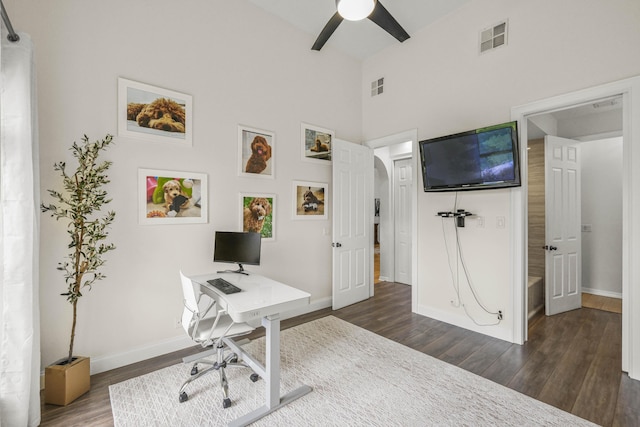 office area with ceiling fan, dark wood-type flooring, and a high ceiling