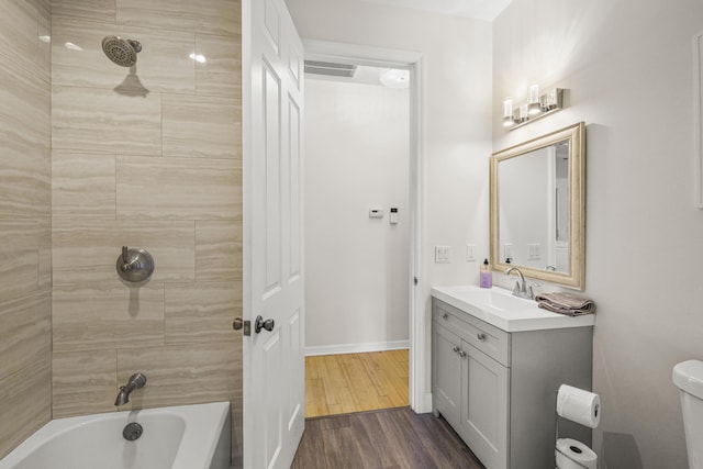 full bathroom with vanity, toilet, wood-type flooring, and tiled shower / bath combo