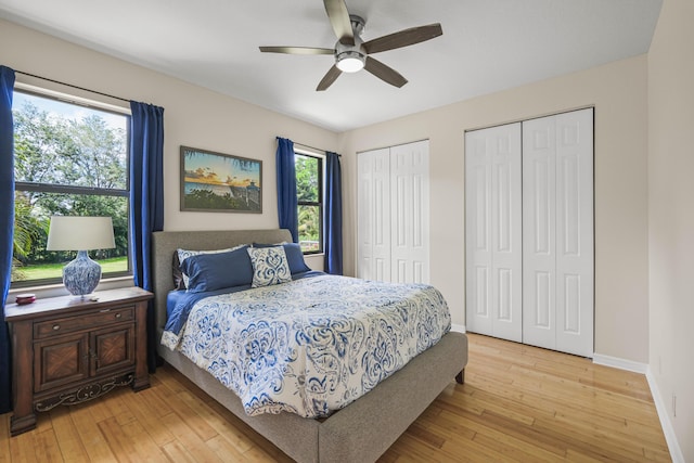 bedroom featuring ceiling fan, light wood-type flooring, and multiple closets