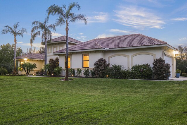 mediterranean / spanish-style home featuring a front yard and a garage