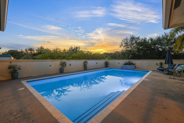 pool at dusk featuring a patio area