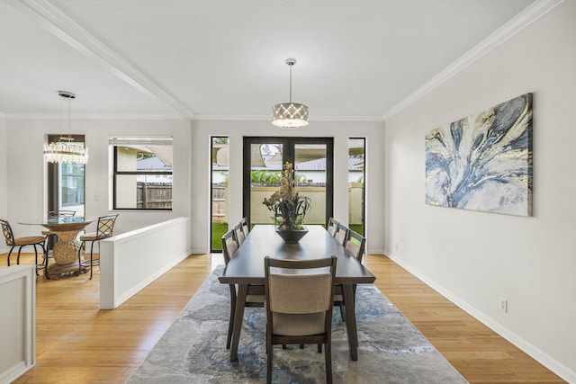 dining area with ornamental molding, light hardwood / wood-style floors, french doors, and an inviting chandelier