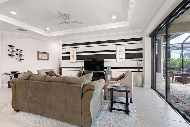 tiled living room with ceiling fan, a raised ceiling, and ornamental molding