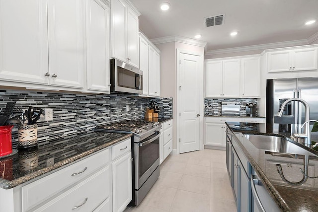 kitchen with sink, white cabinetry, stainless steel appliances, and dark stone counters