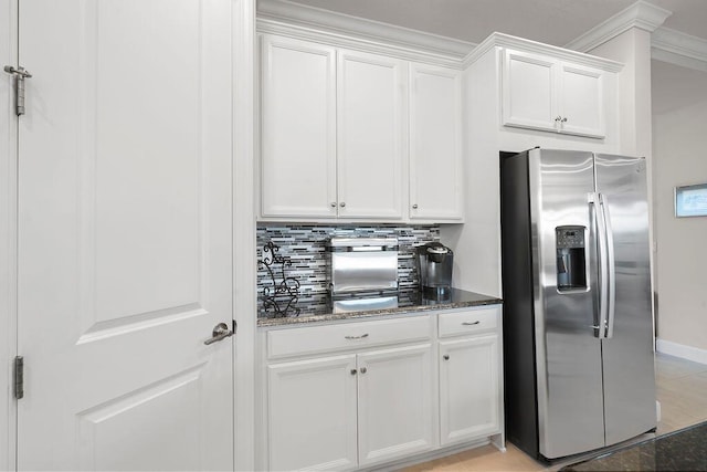 kitchen with tasteful backsplash, ornamental molding, dark stone counters, stainless steel fridge with ice dispenser, and white cabinetry