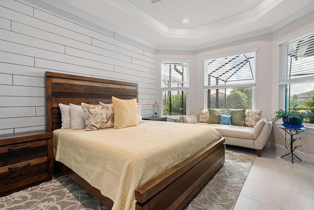 bedroom with a tray ceiling, wood walls, crown molding, and tile patterned floors