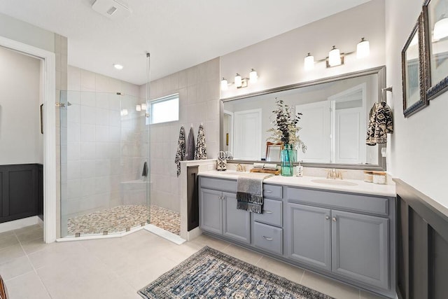 bathroom featuring a tile shower, tile patterned flooring, and vanity