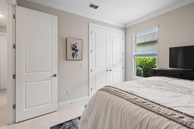 bedroom with light tile patterned floors, crown molding, and a closet