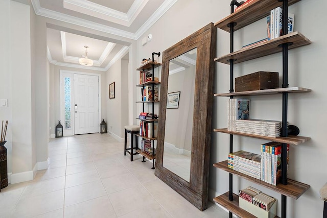 tiled foyer featuring a tray ceiling and ornamental molding