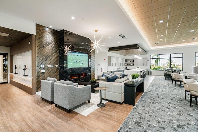 living room with light wood-type flooring, a notable chandelier, and a premium fireplace