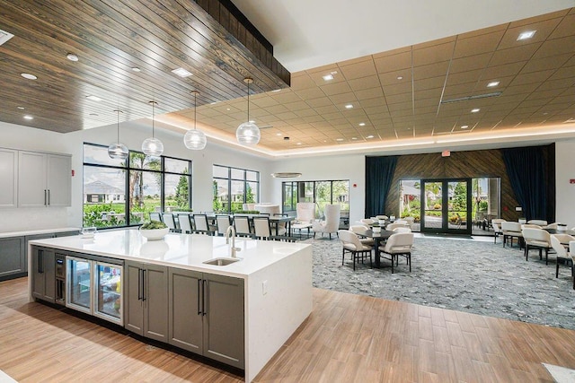 kitchen featuring light wood-type flooring, sink, pendant lighting, gray cabinets, and wine cooler