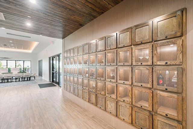 hall featuring lofted ceiling, light hardwood / wood-style flooring, and wooden ceiling