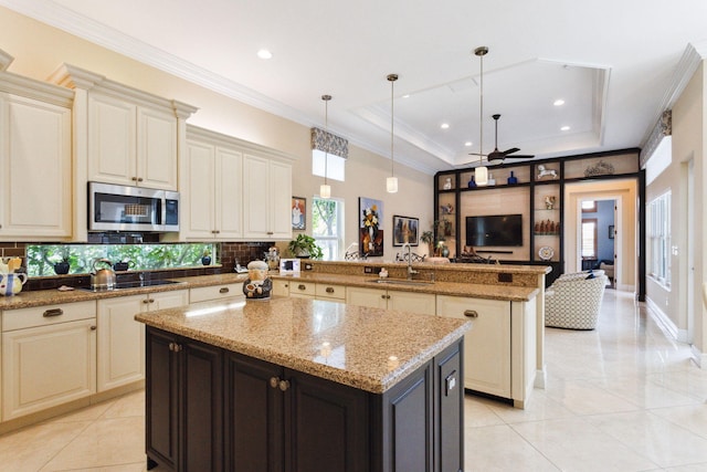 kitchen featuring black cooktop, a raised ceiling, sink, a kitchen island, and hanging light fixtures