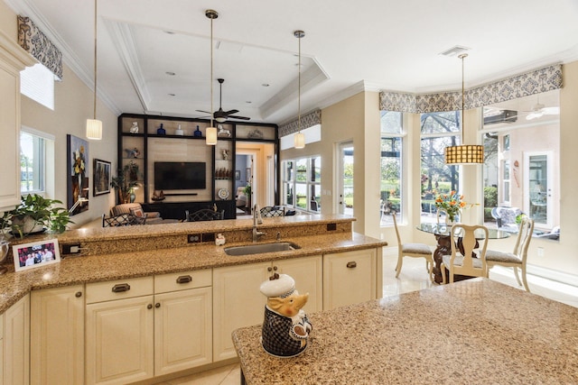 kitchen with light stone countertops, a raised ceiling, ceiling fan, sink, and pendant lighting