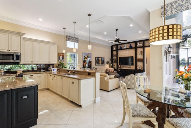 kitchen featuring backsplash, sink, hanging light fixtures, ceiling fan, and light stone counters