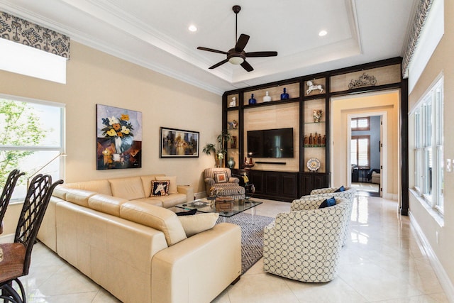 living room with a tray ceiling, ceiling fan, and ornamental molding