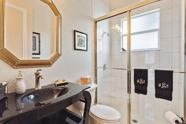 bathroom featuring toilet, a shower with door, and sink