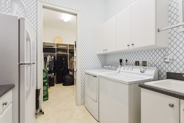 washroom with washer and dryer, light tile patterned floors, and cabinets