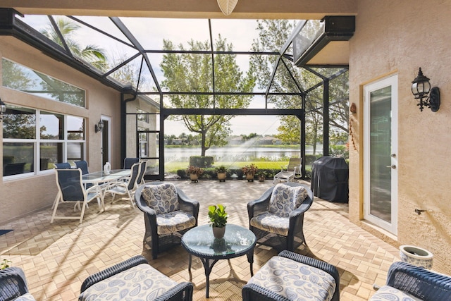 view of patio with glass enclosure, a grill, and a water view