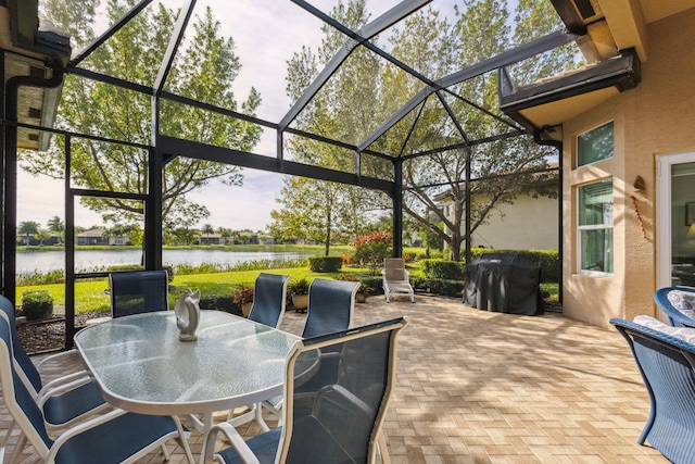 view of patio / terrace with a lanai, area for grilling, and a water view