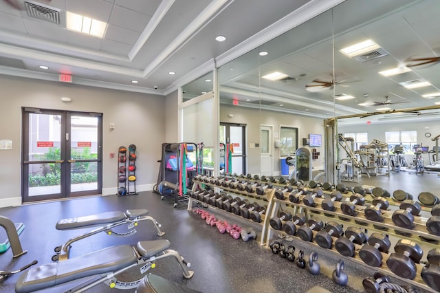 exercise room featuring ceiling fan, french doors, ornamental molding, and a tray ceiling