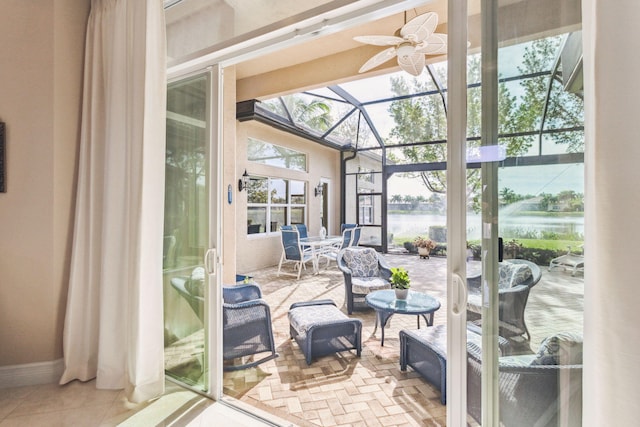 sunroom / solarium with ceiling fan and a water view