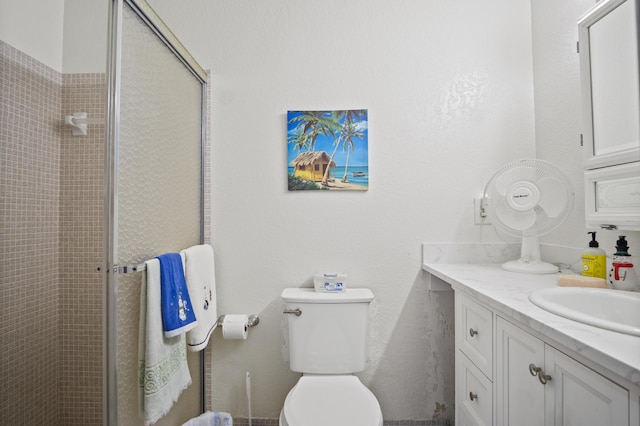 bathroom featuring a shower with door, vanity, and toilet